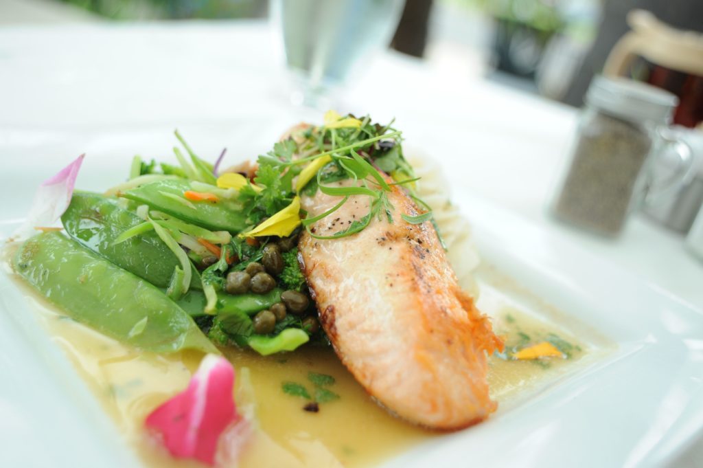 Crown Bistro offers Coronado outdoor dining options. Pictured: salmon on plate with fresh salad and broth
